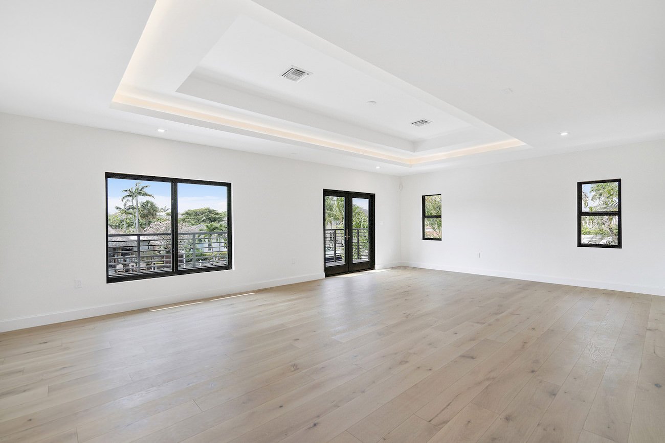 Empty large bedroom with greenery outside.