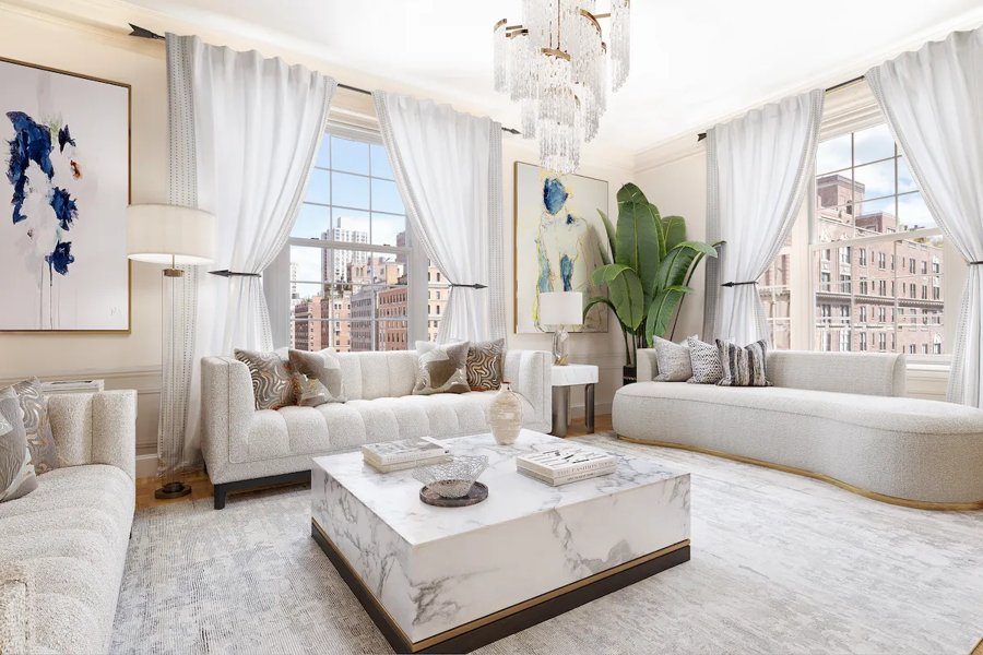 Virtually staged NY town home living room with a white sectional, modern staircase, and abstract artwork