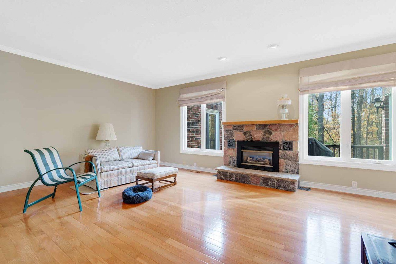 Minimal living space with wood flooring, a striped sofa, and stone fireplace before furniture replacement.