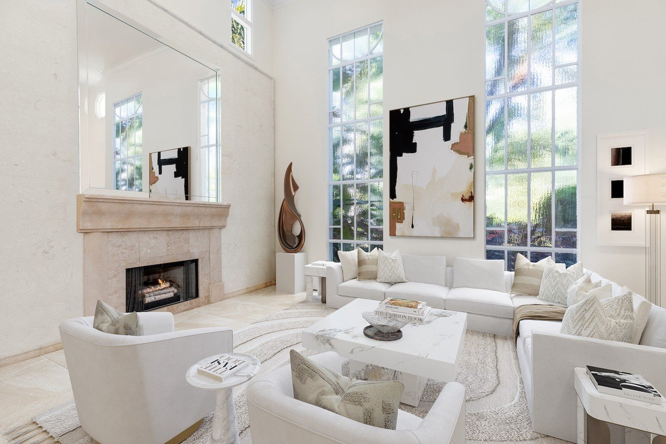 Furniture-replaced living room showcasing a white sectional, sculptural decor, and abstract wall art under large arched windows.