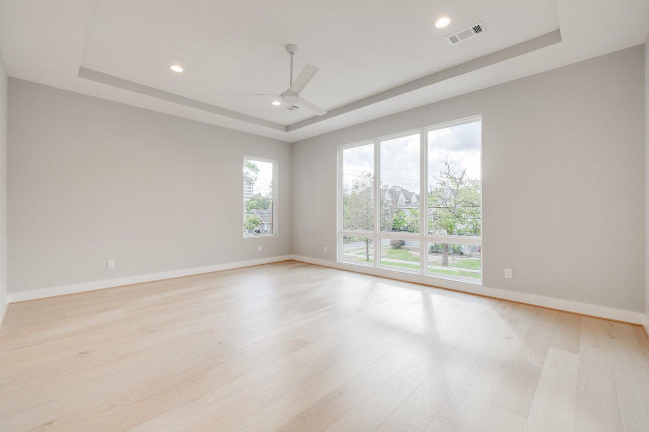 Empty bedroom with large windows and light hardwood flooring