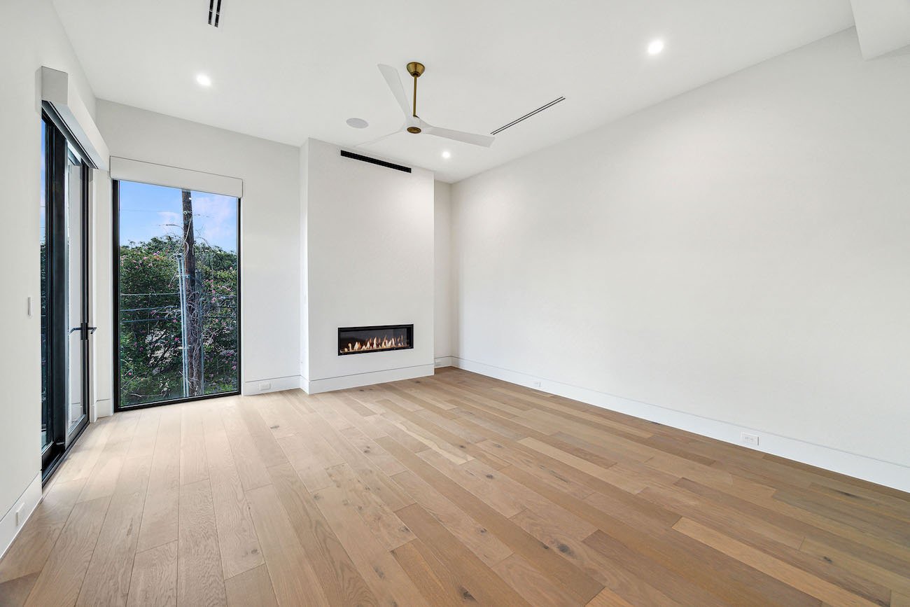 Empty bedroom with fireplace showing greenery outside in texas