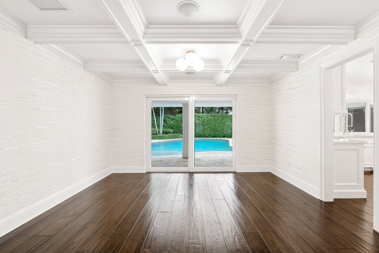 White-walled dining area with dark wood floors and pool view