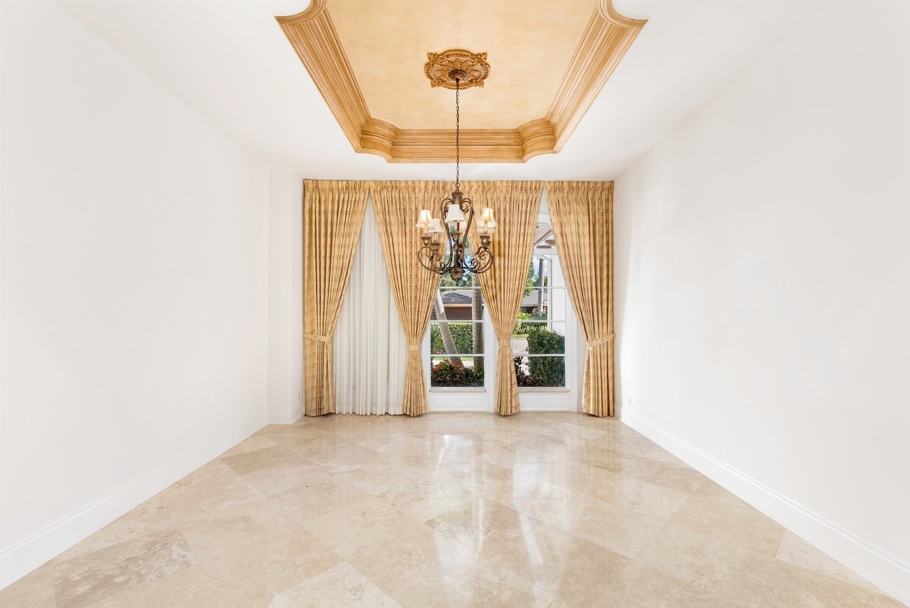 Empty dining room with gold drapes and chandelier