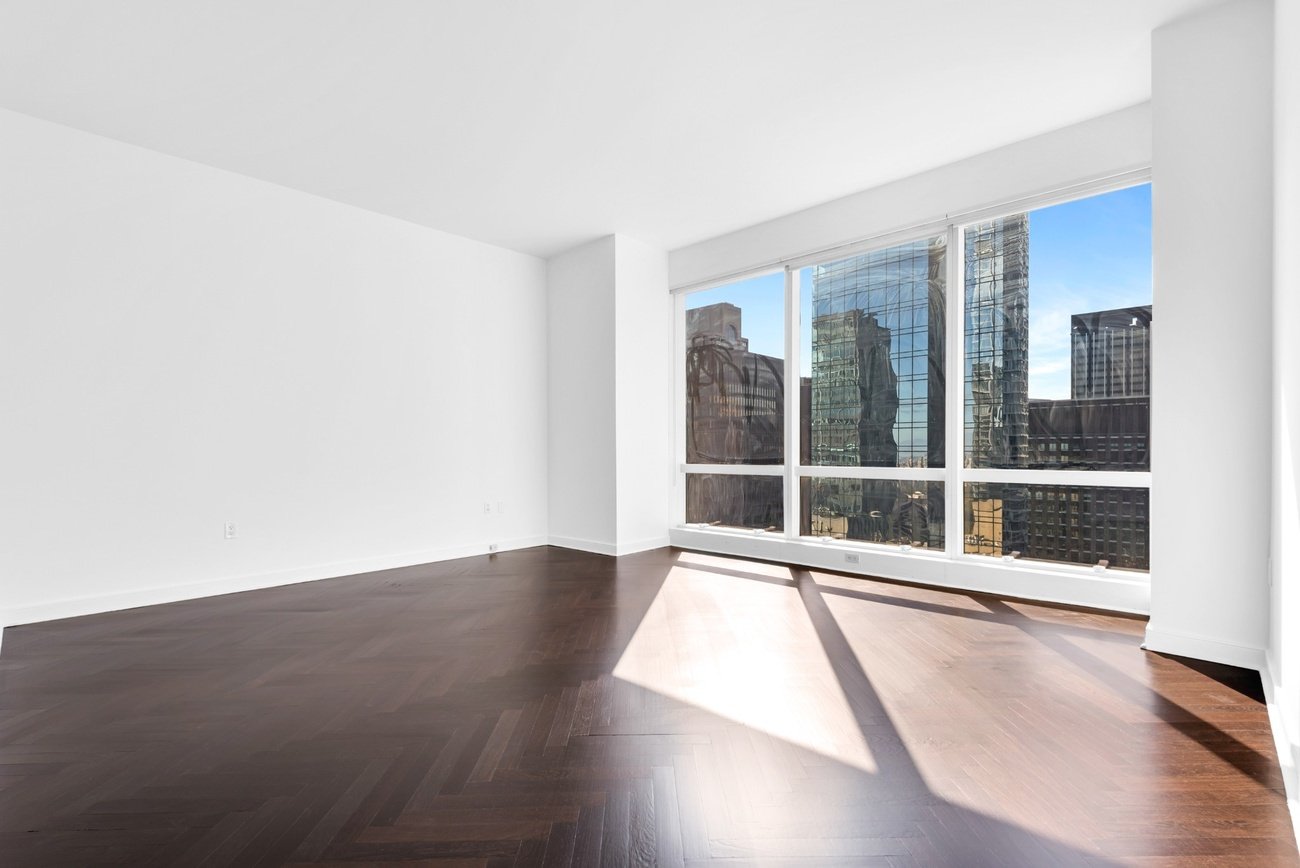 Empty living room with dark herringbone floors and city view