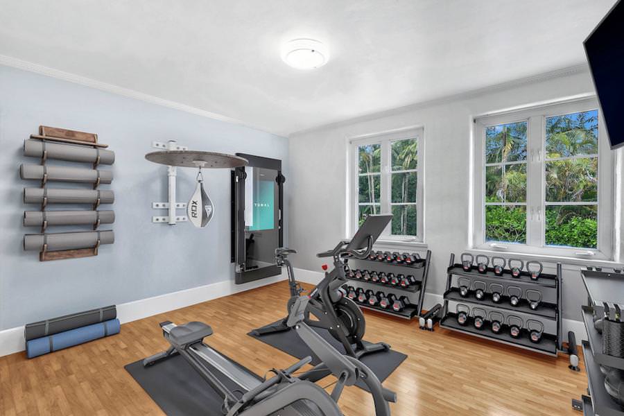 virtually staged home gym with Tonal system, free weights, and punching bag in a light-filled room.