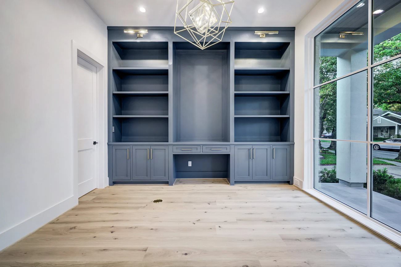 Unfurnished home office with navy built-in shelving and large front-facing windows