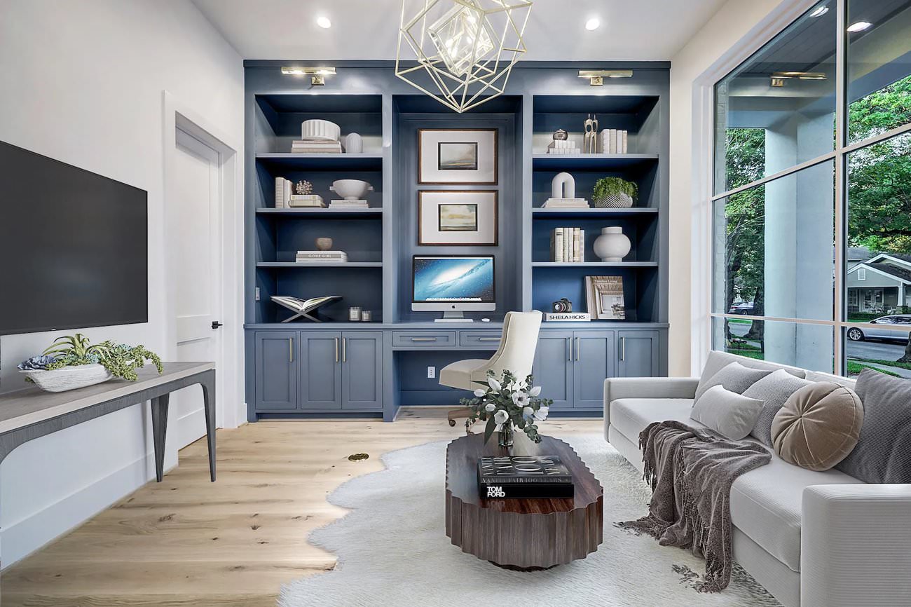 Virtual staging of a stylish home office with navy built-ins, desk setup, white sofa, and natural light