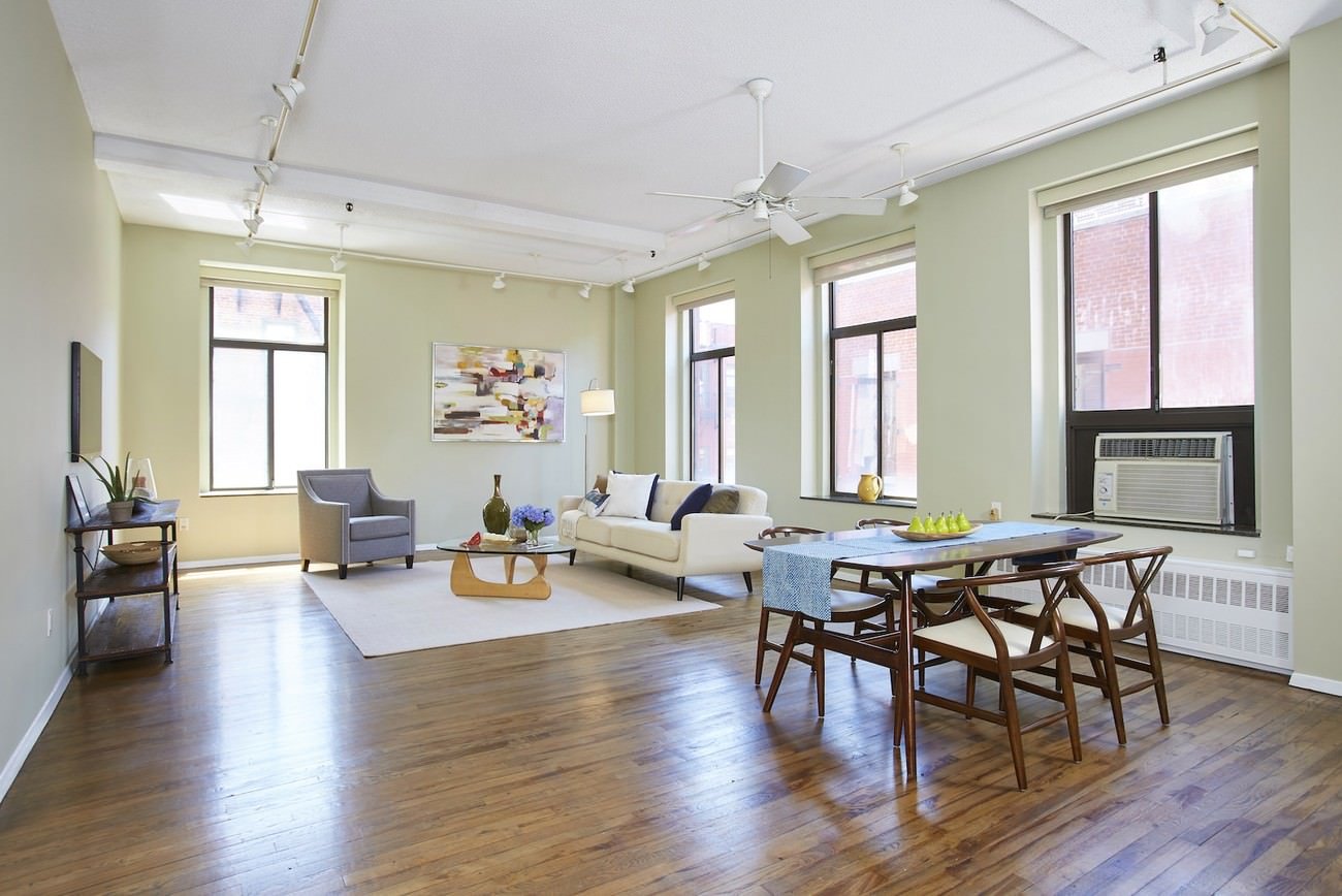 Spacious loft with exposed beams and large windows, shown before virtual staging