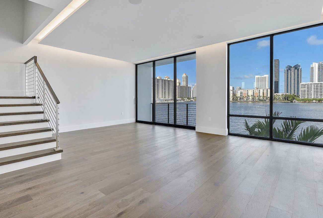 Unfurnished Miami great room with large windows, water view, and hardwood floors