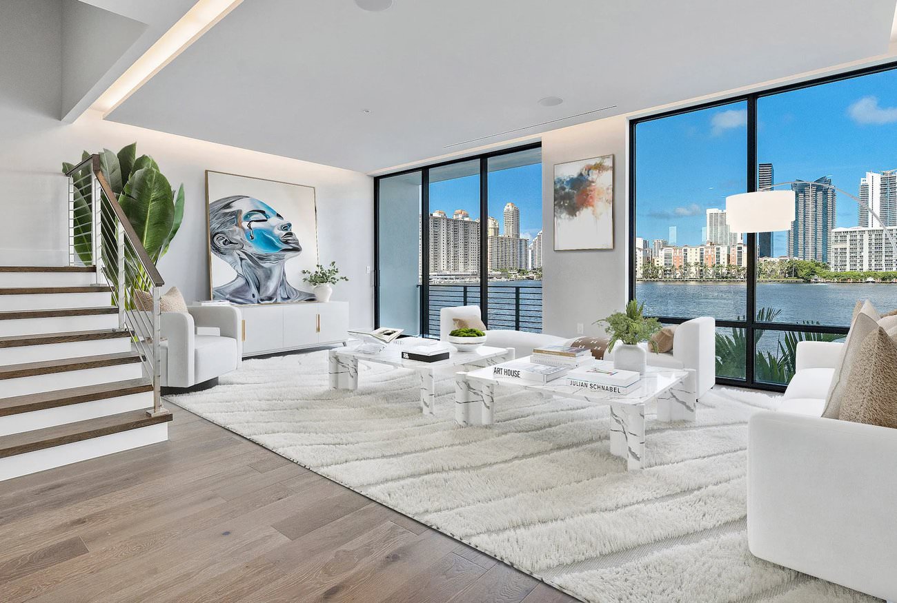 Virtual staging of a Miami great room with large windows, white furniture, and a dramatic city and water view