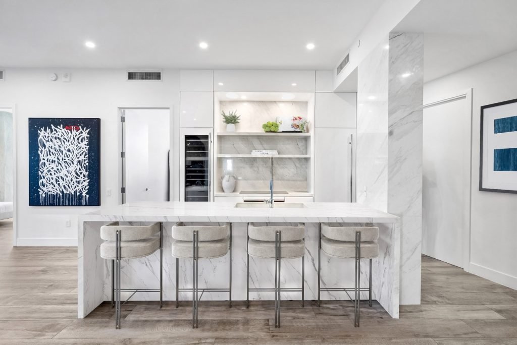 Luxury kitchen with full-height marble island, built-in shelves, and sleek modern bar stools