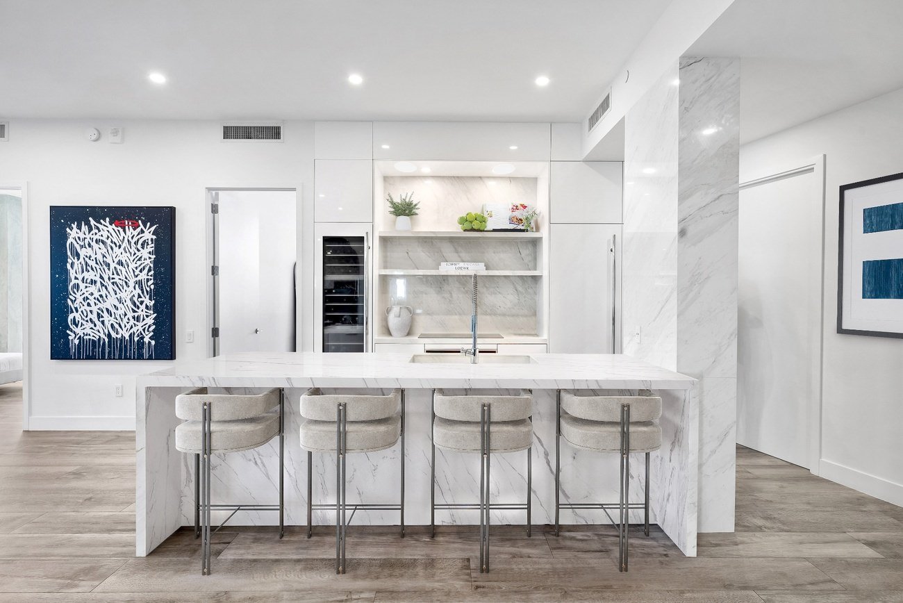 Luxury kitchen with full-height marble island, built-in shelves, and sleek modern bar stools