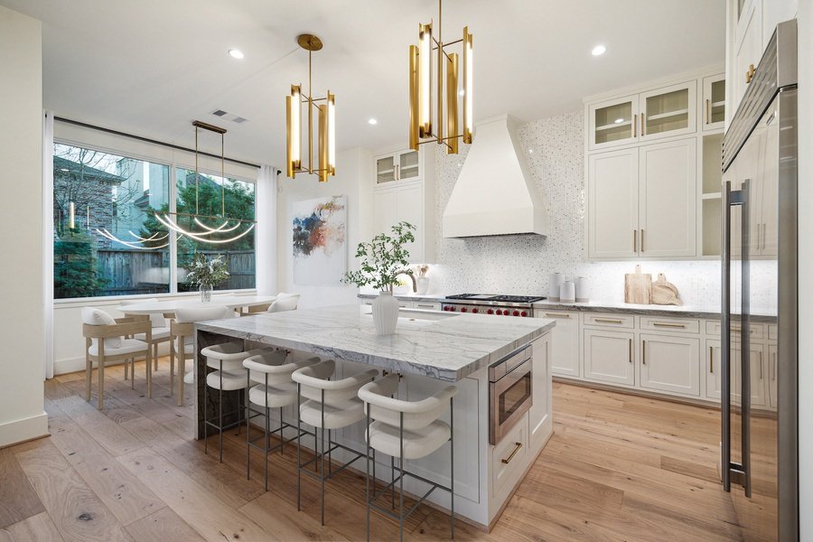 Bright kitchen with a large marble island, gold pendant lighting, and modern dining area