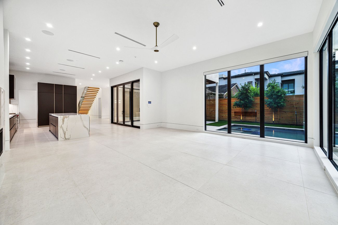 Unfurnished modern open living room with large windows, marble kitchen island, and neutral tile flooring