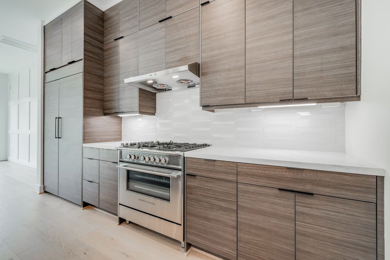 Empty modern kitchen with clean wood cabinetry and stainless steel appliances before staging.