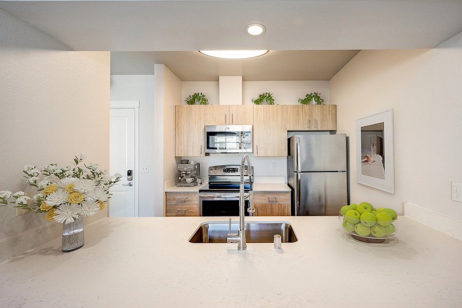 Virtually staged compact kitchen with stainless steel appliances and bright white counters