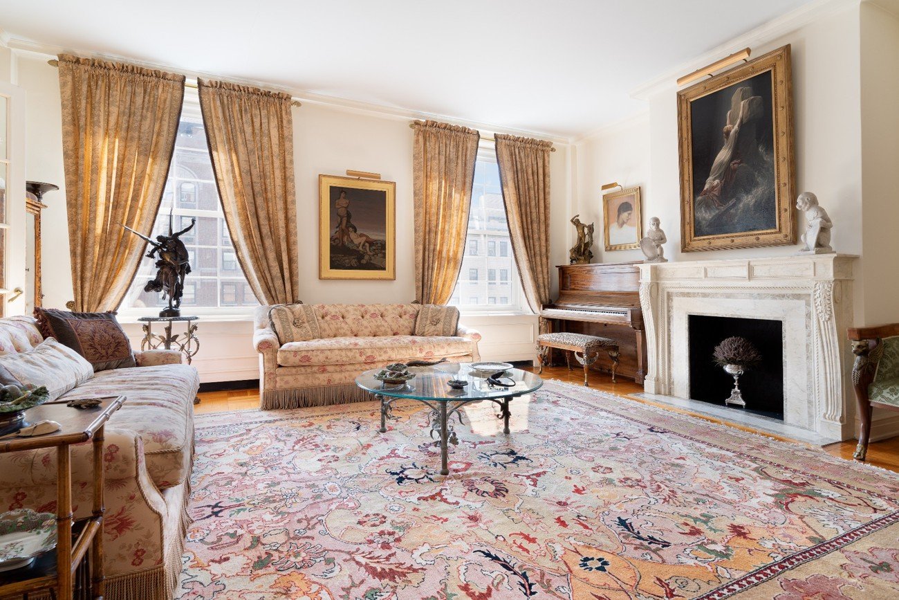 Traditional living room with floral sofas, gold drapes, and classical artwork before furniture replacement.
