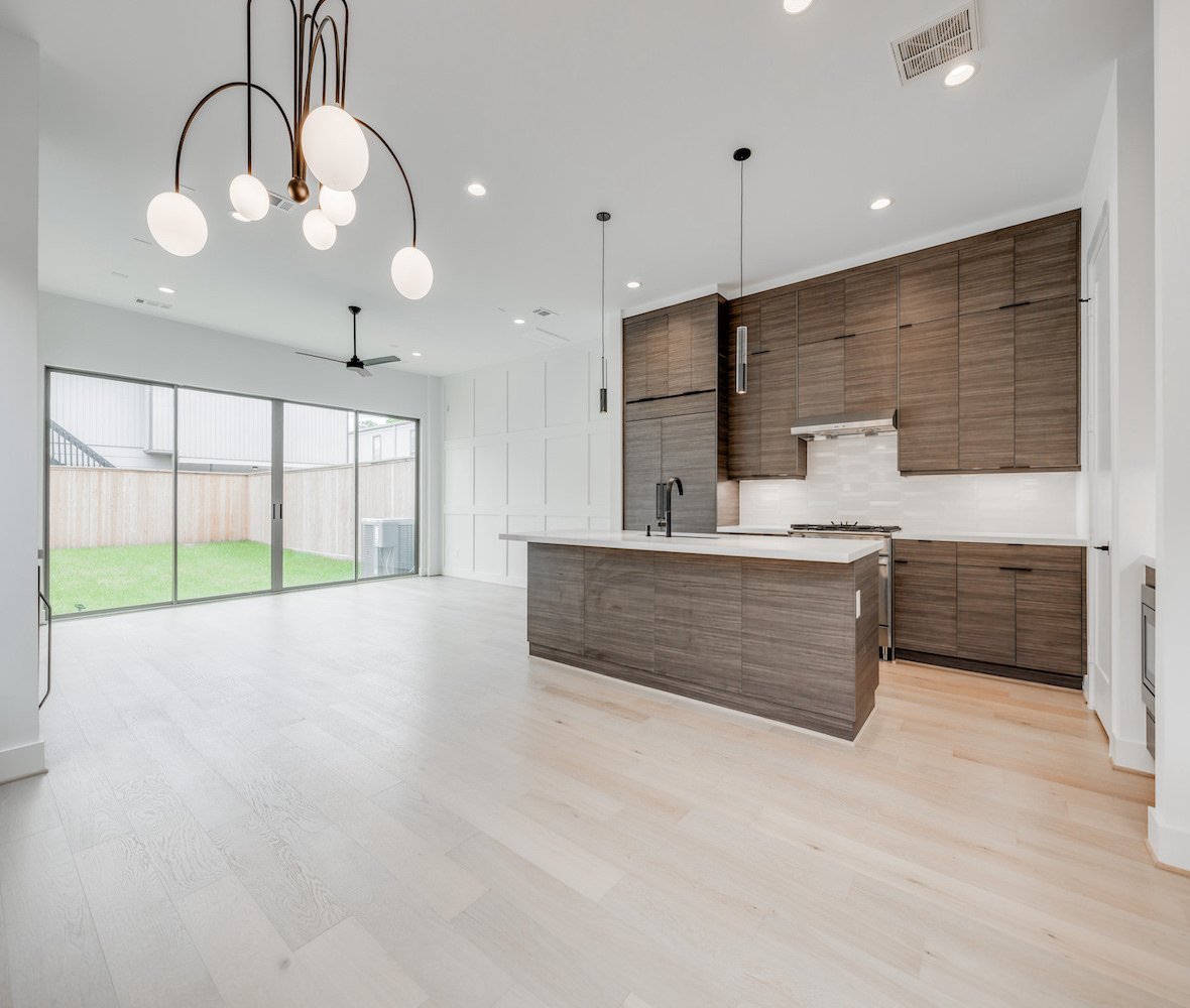 Empty open-concept room with wood cabinets and large windows, before virtual staging.