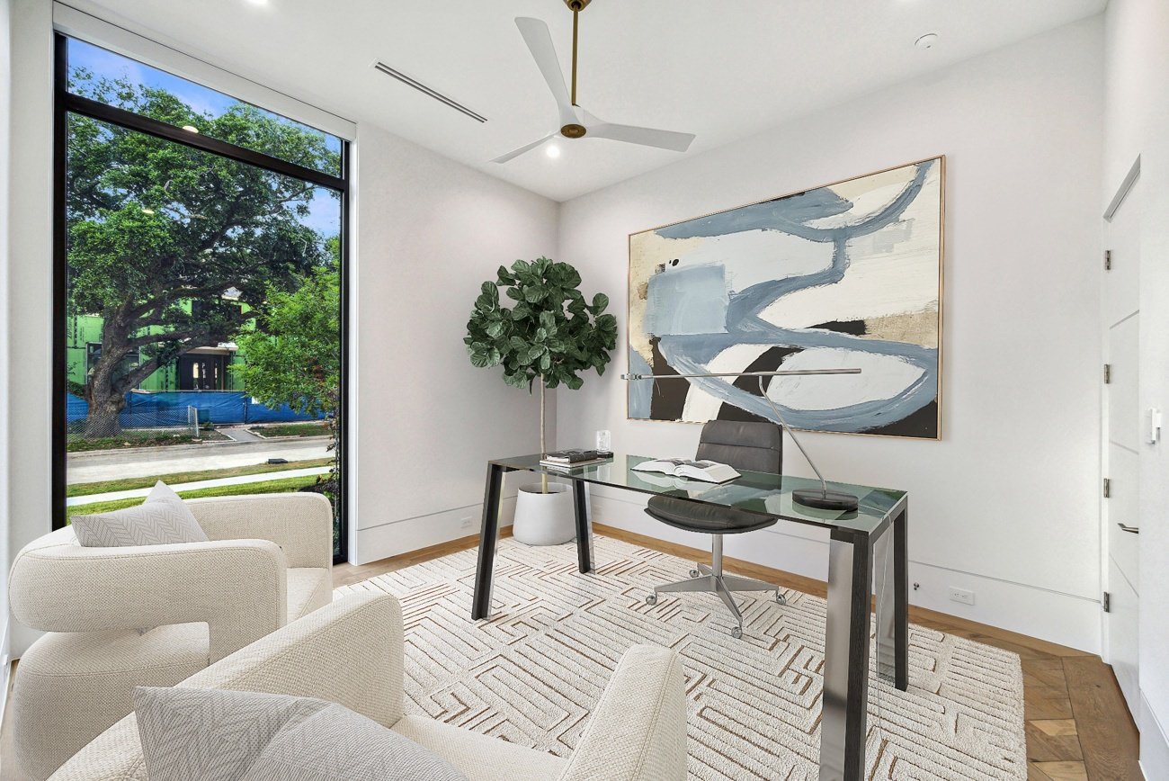 Virtual home office staging with abstract artwork and floor-to-ceiling window
