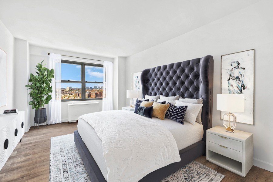 Virtual staging of a bedroom with a tufted headboard, white bedding, and city view